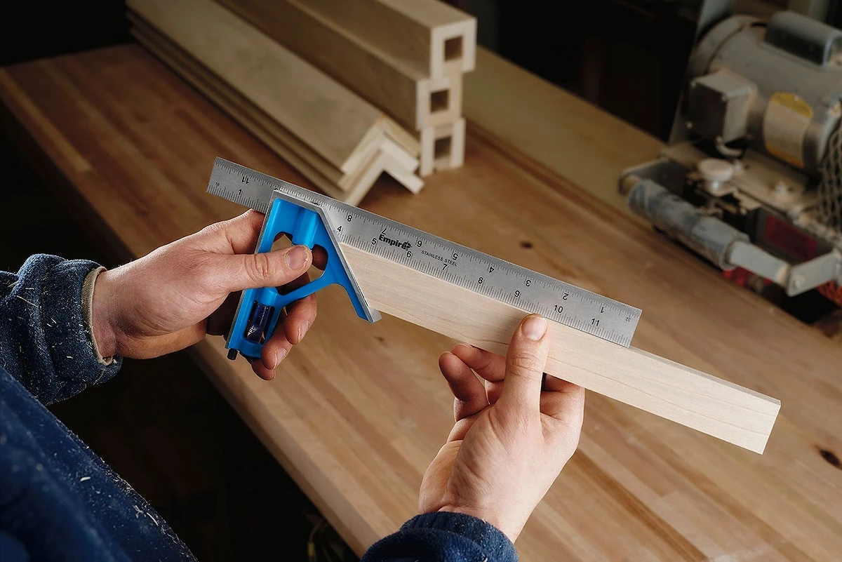 Carpenter using a combination square to measure a wooden workpiece 