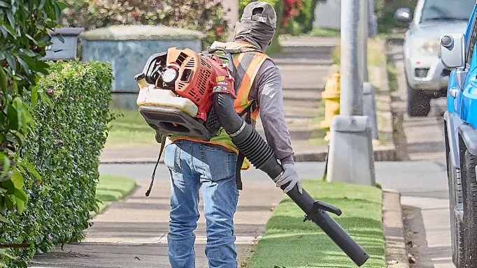 A professional user carrying a backpack commercial leaf blower on his back
