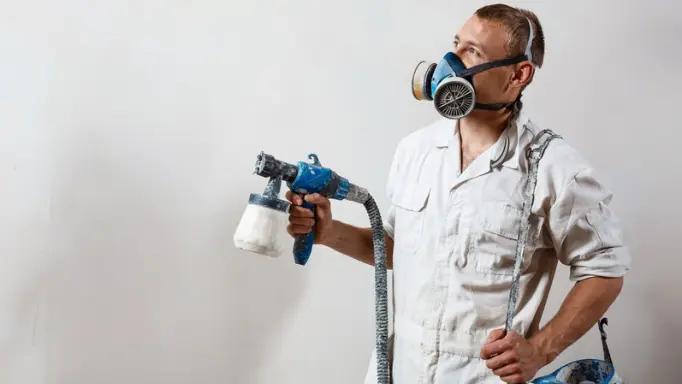 A man painting a wall with an air spray gun