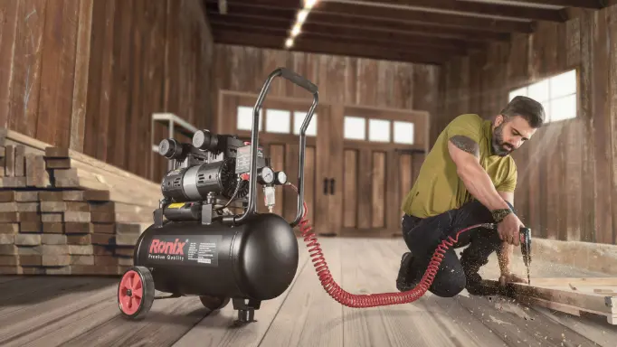 A man using one of the Ronix best air compressors to power up a pneumatic tool