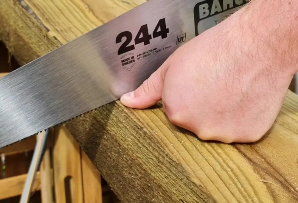 person cutting a sleeper with a hand saw