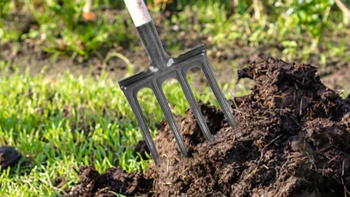 a garden fork left in a dirt pile