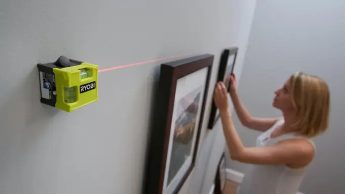 A woman using one of the best laser levels for hanging pictures
