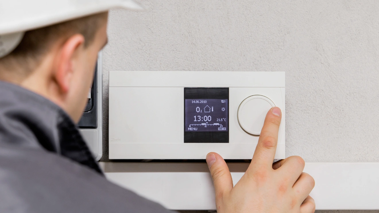 A man checking an AC’s Thermostat