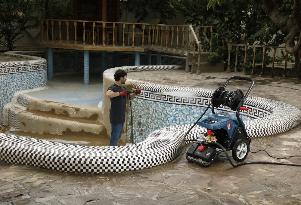 Person washing the walls of a pool with a pressure washer