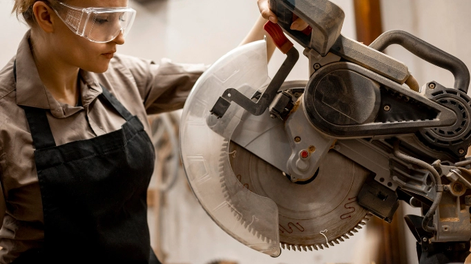 A woman working with a miter saw with a blade guard