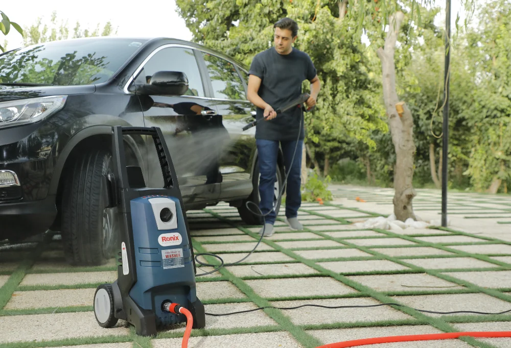 person washing a car with a pressure washer