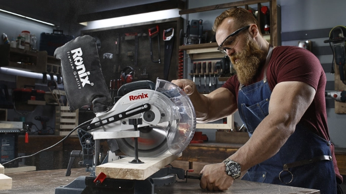 A person cutting a piece of wood with a miter saw