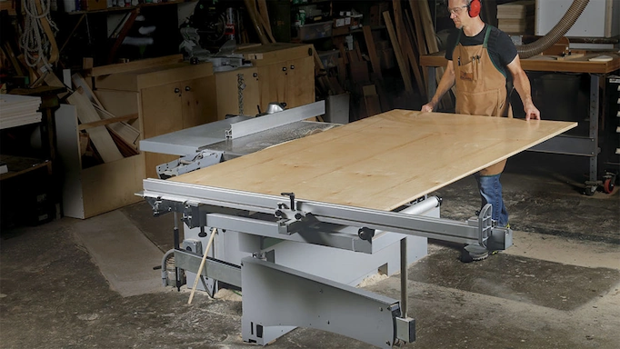 A sliding type of table saw is being used)