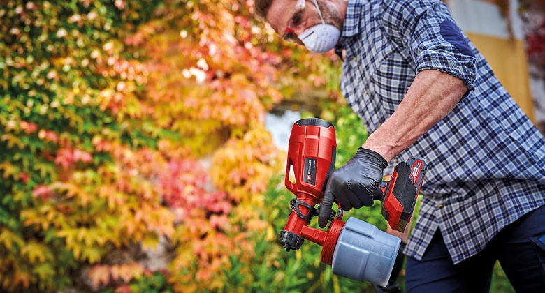 Man using a cordless paint sprayer outdoors