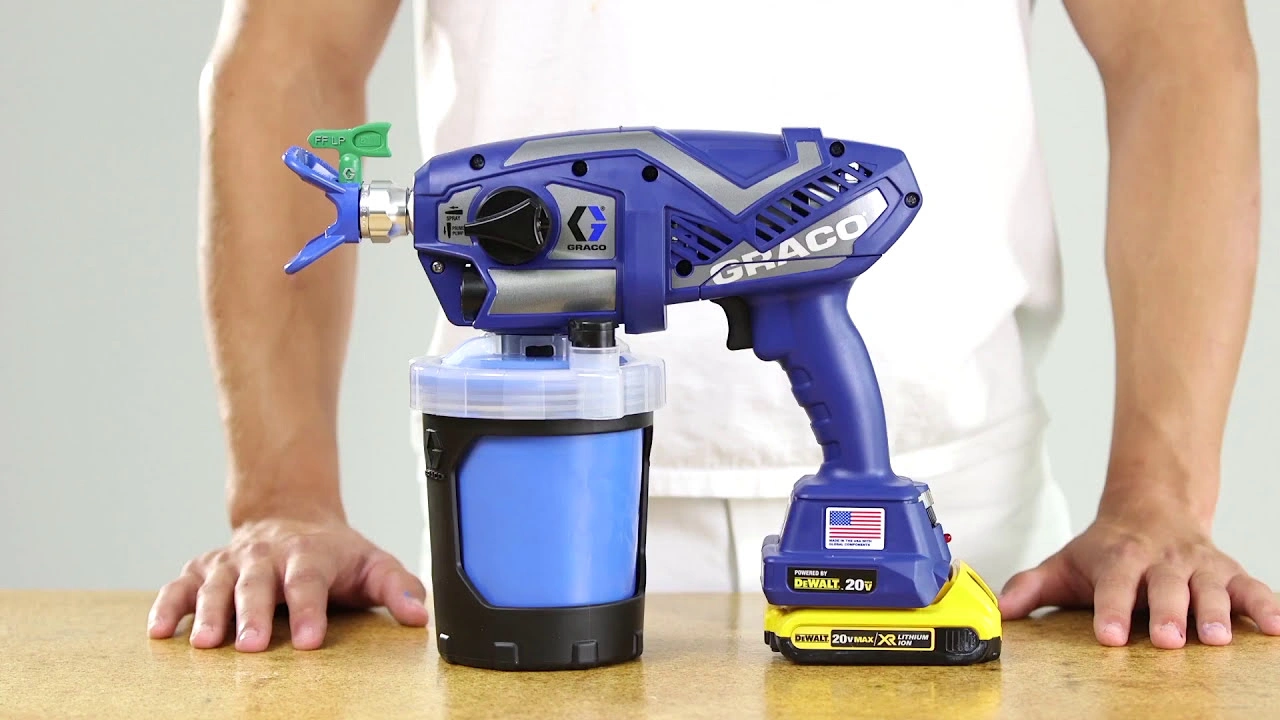 Cordless paint sprayer on a table with a person standing behind it.