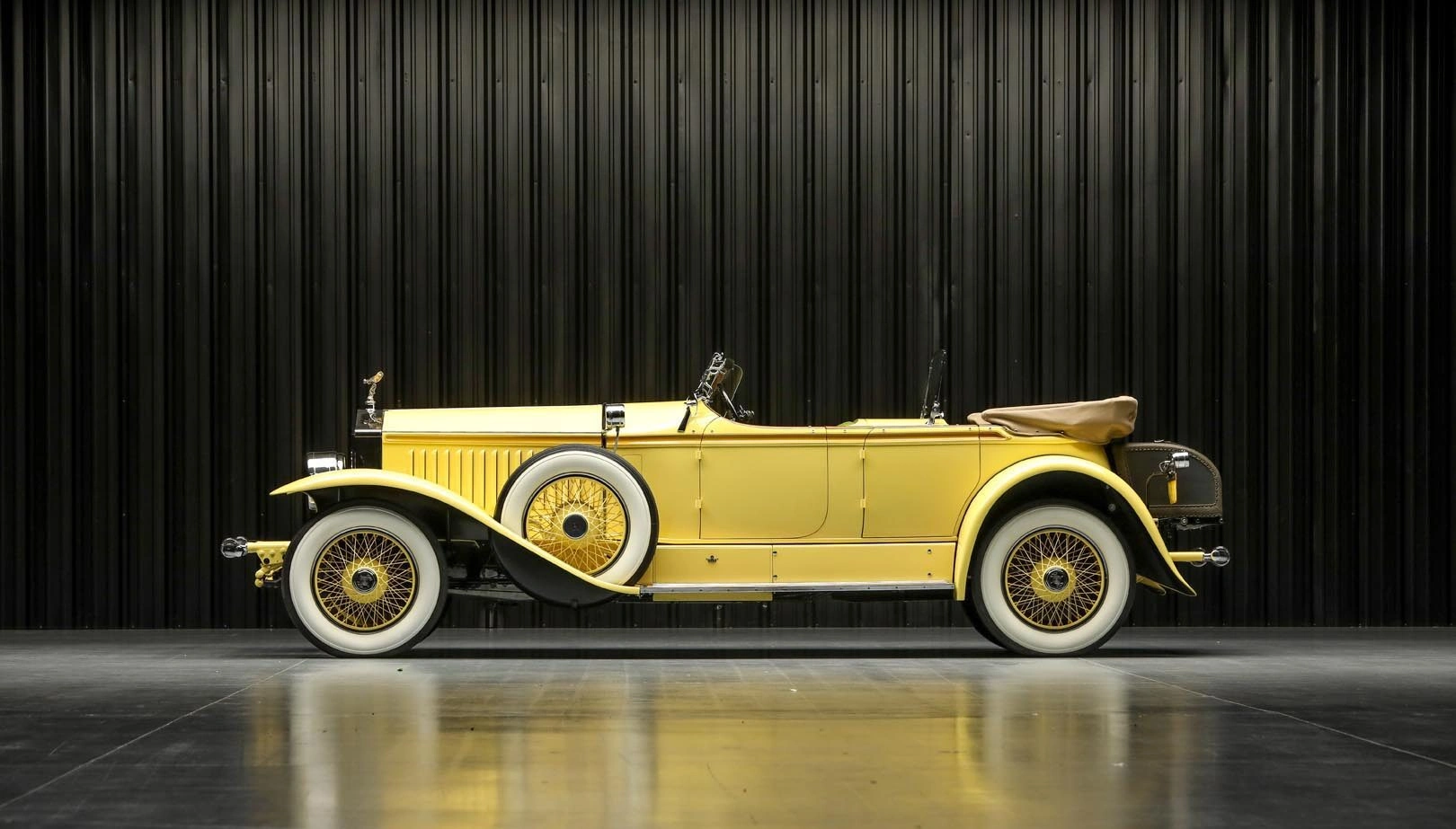 Vintage yellow convertible car displayed against a black background.