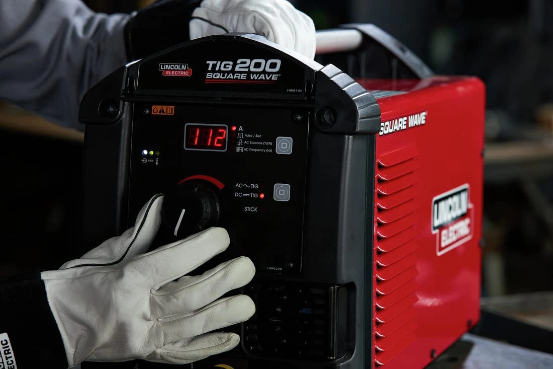 A photo of the operators’ hands on a Lincoln Electric Square Wave® 200 TIG Welder