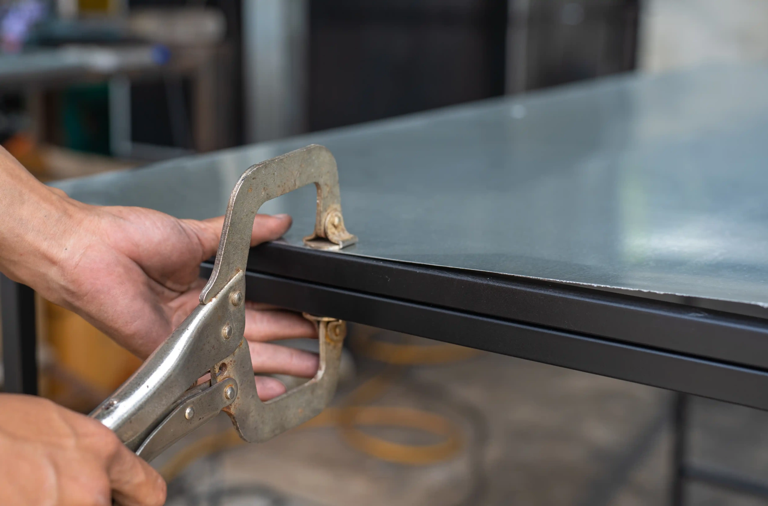 locking pliers gripping the edge of a metal sheet