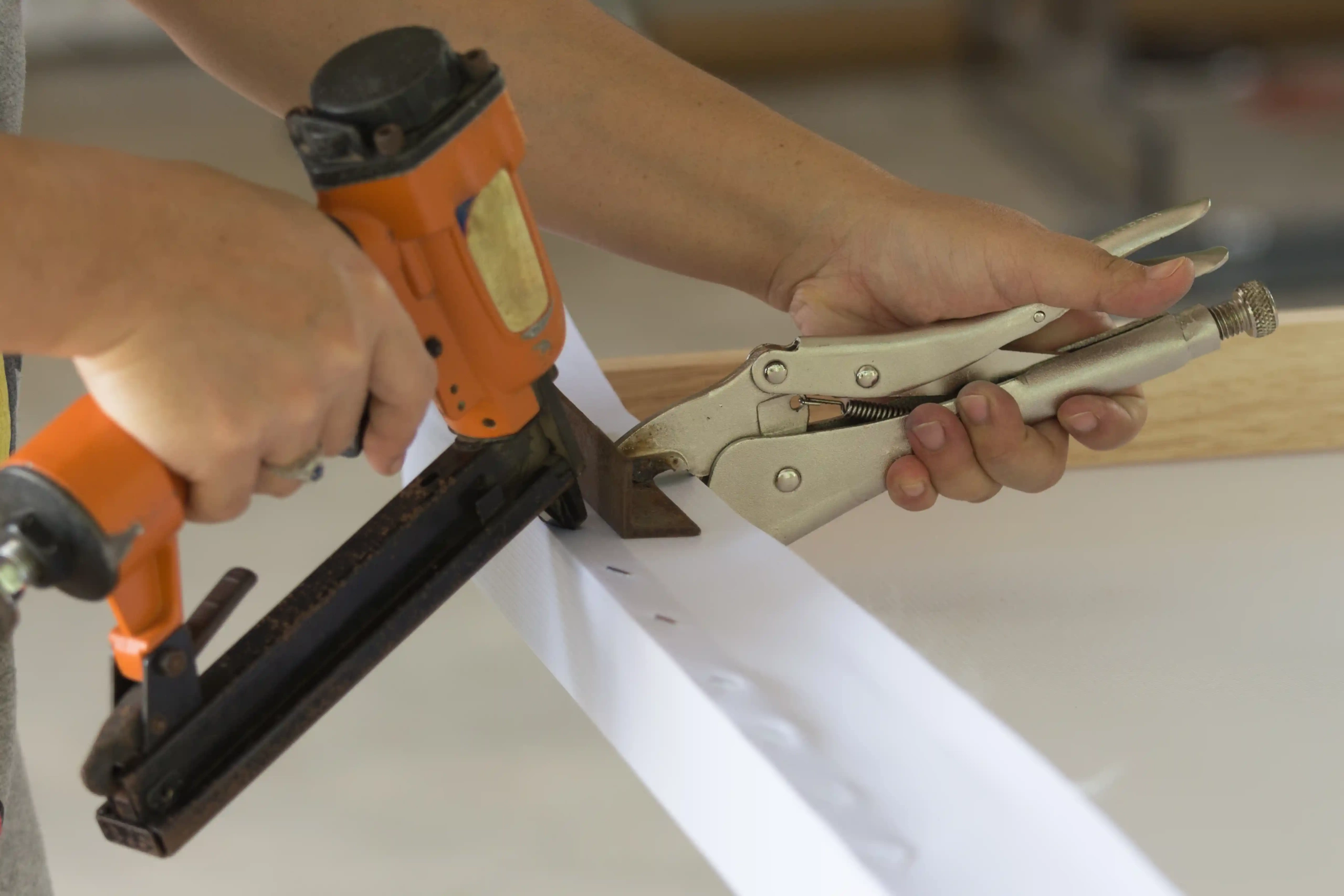 Locking pliers holding fabric taut while using a stapler