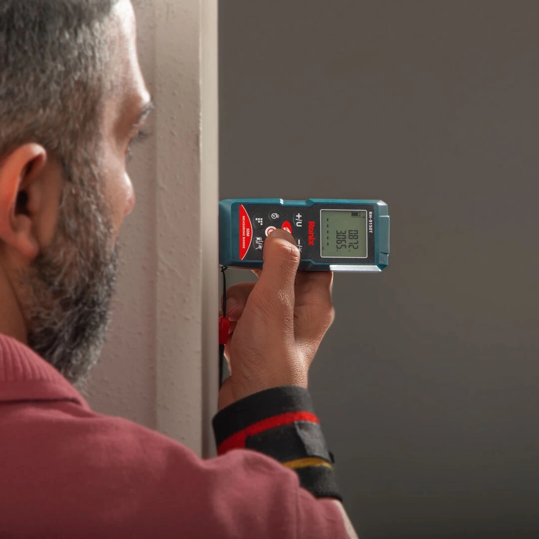 A man uses laser tape measure inside