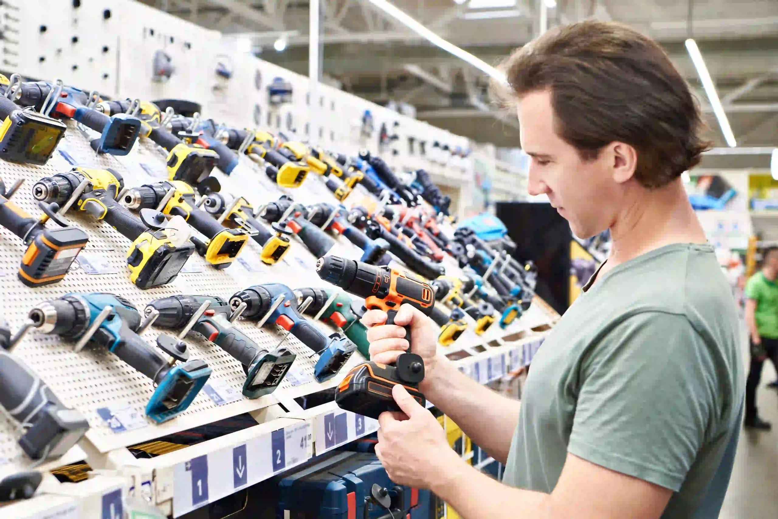 Customer examining electric screwdrivers on display in a hardware store