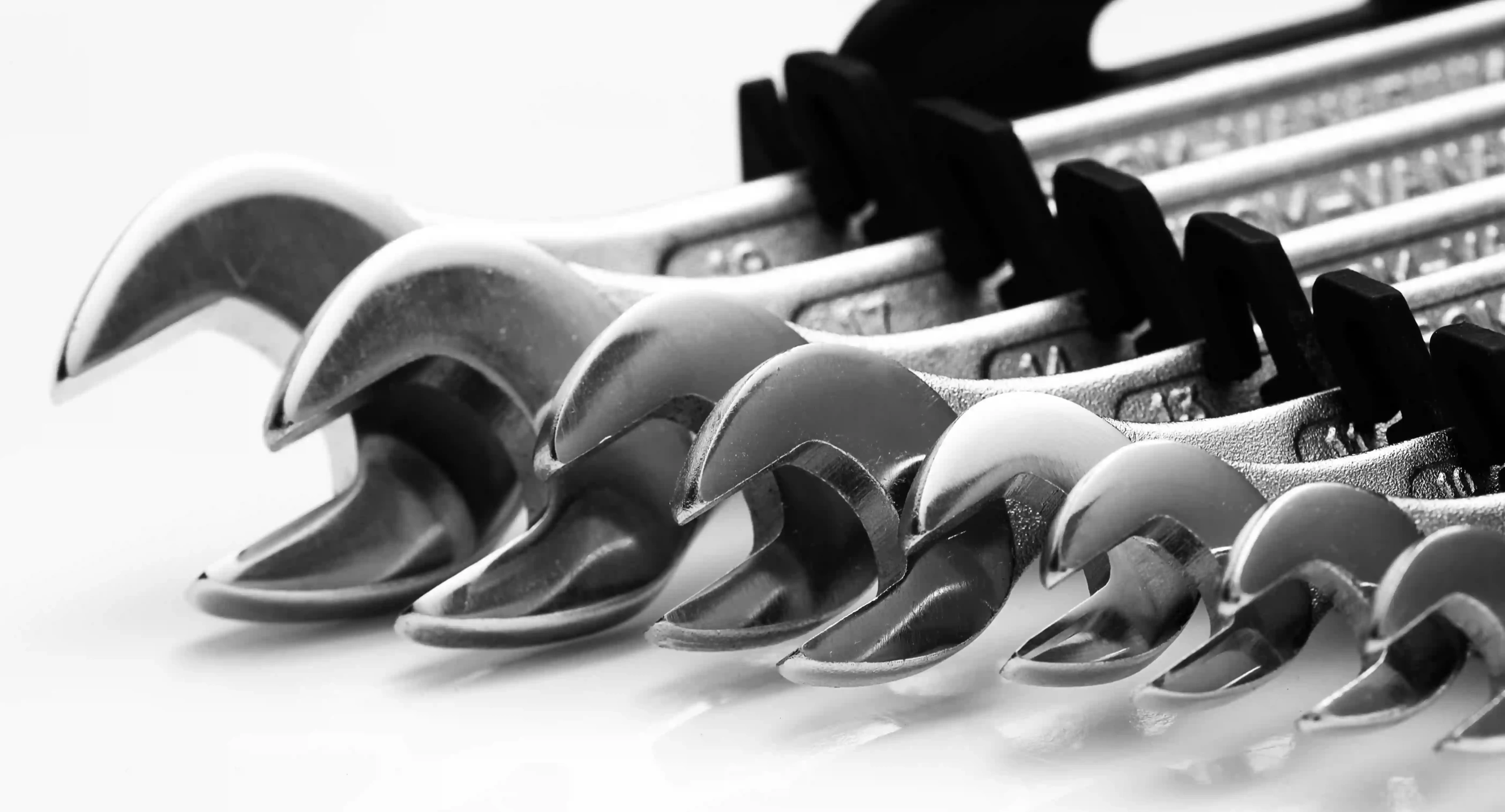 A black-and-white close-up of a set of wrenches arranged in ascending size.