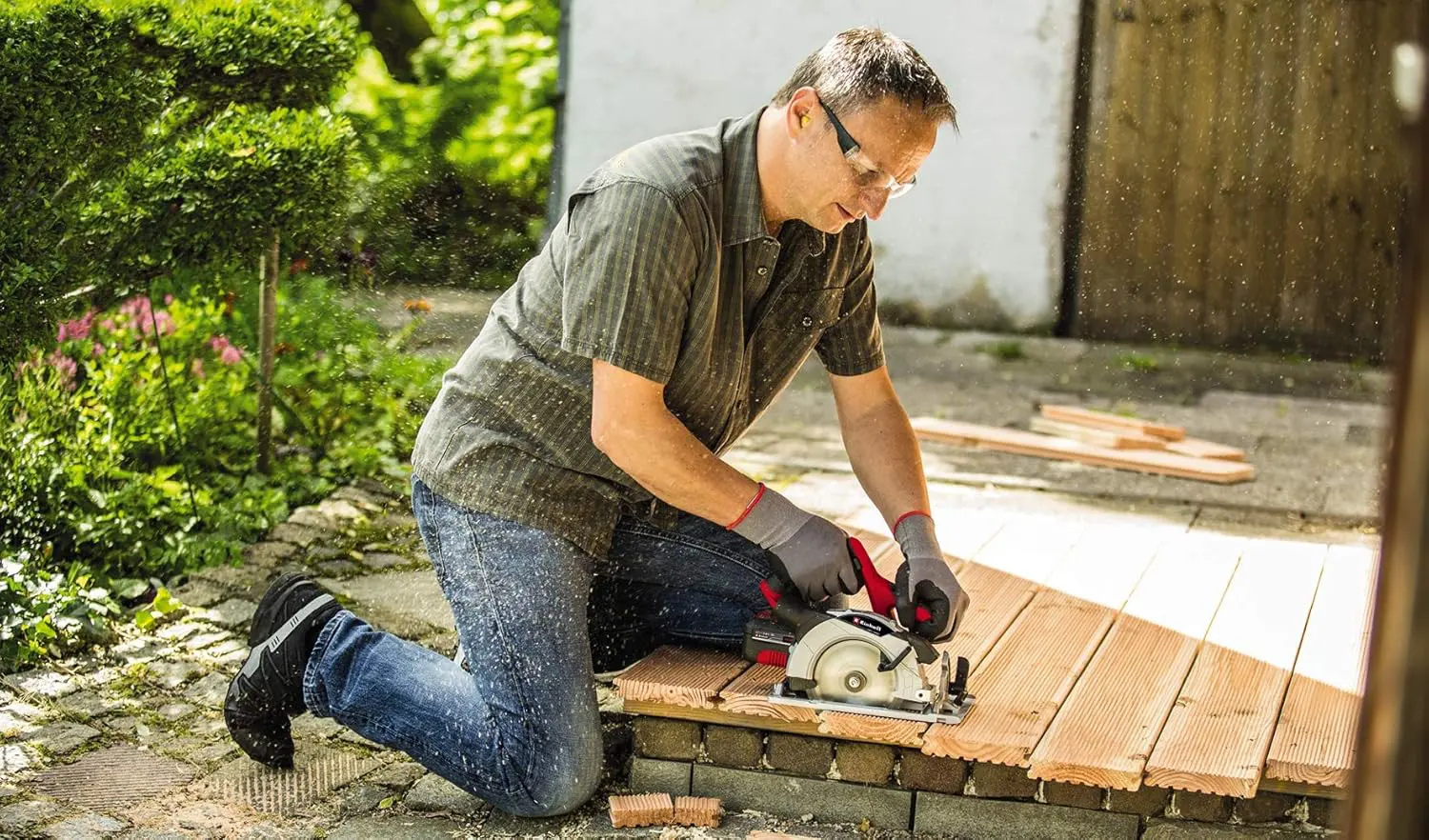 A man is cutting a wood board with Einhell cordless circular saw