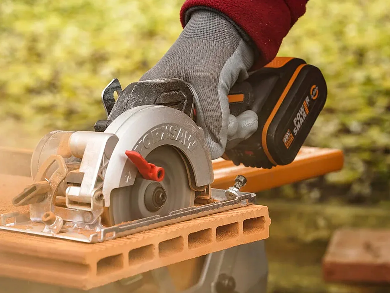 A photo of a hand cutting wood with Worx cordless circular saw