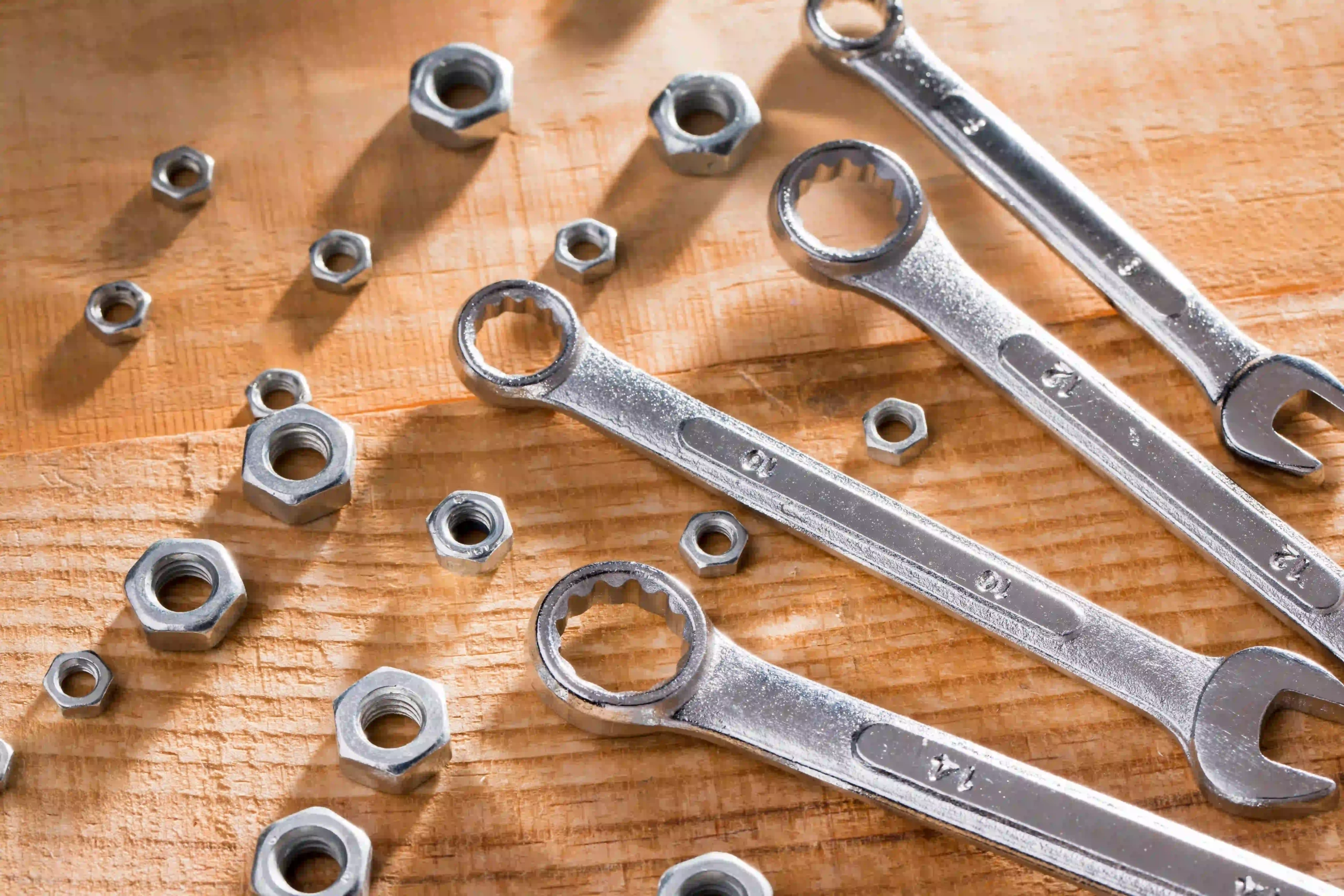 wrenches and hex nuts scattered on a wooden surface.