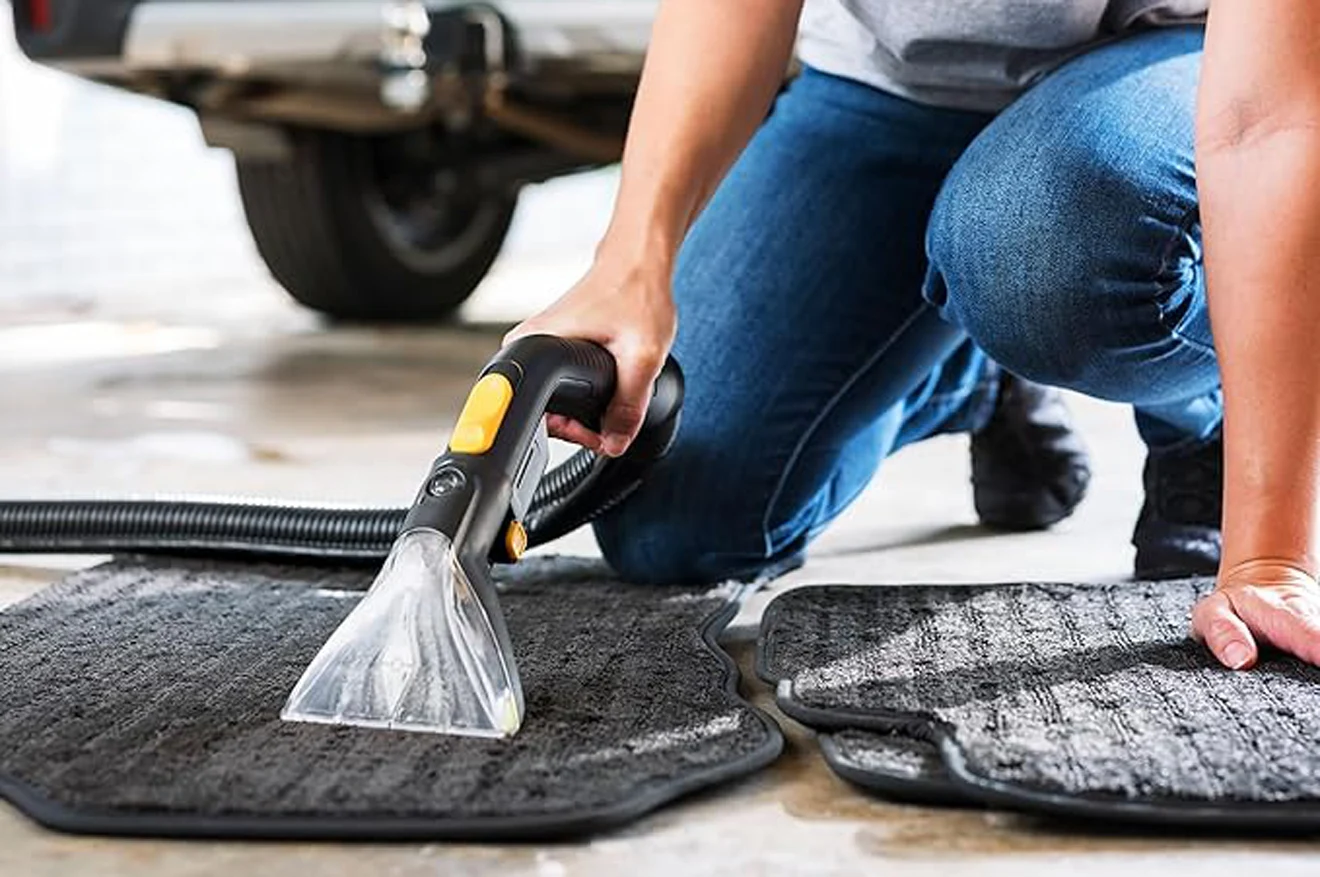 An operator is working with an industrial vacuum cleaner to clean car’s carpets