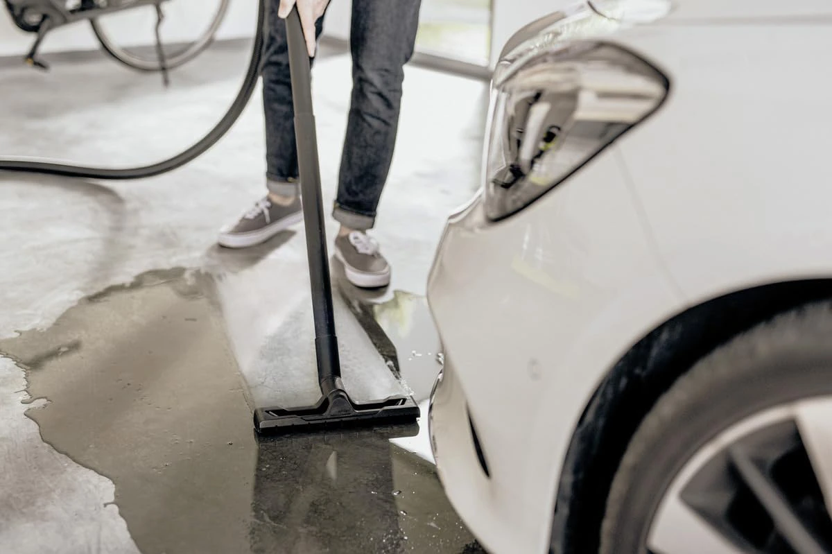 An operator is cleaning wet floor using an industrial vacuum cleaner