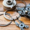 snap ring pliers gripping a circlip, with various snap rings on a wooden surface.