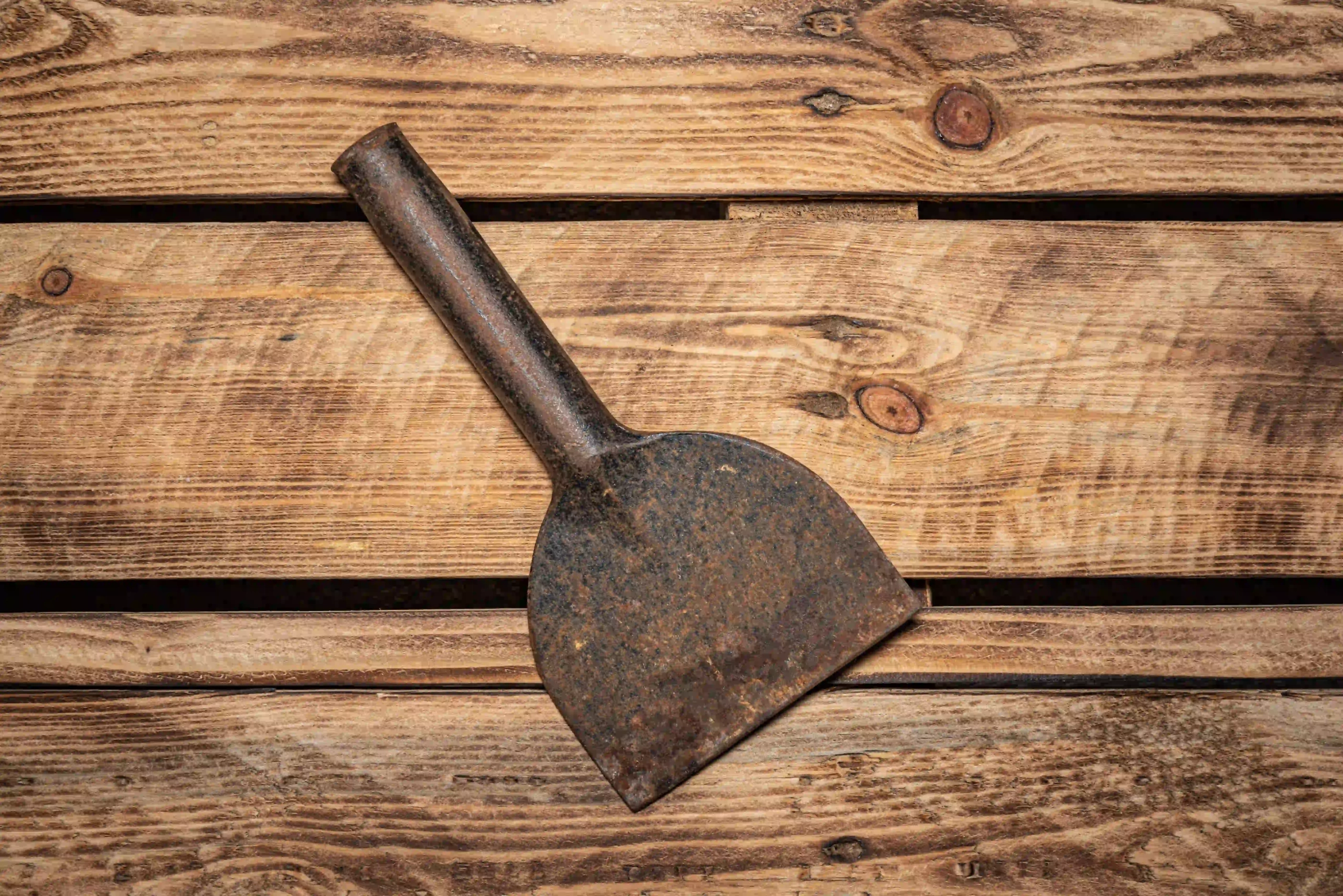 Rusty masonry chisel on a wooden surface.