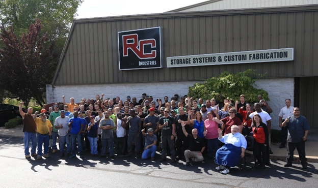 Large group of employees posing outside RC Industries building