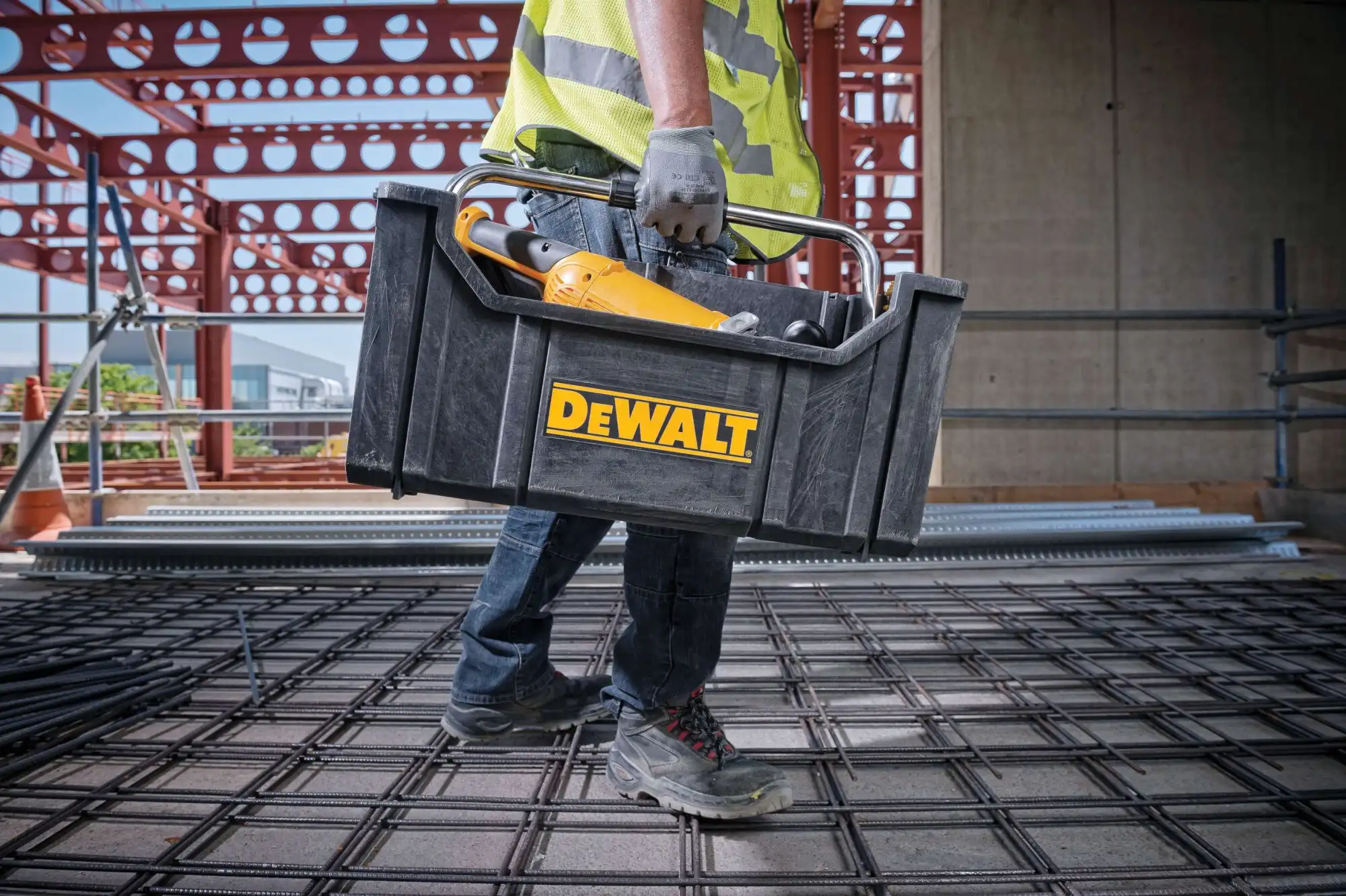 Worker carrying DeWalt toolbox on construction site