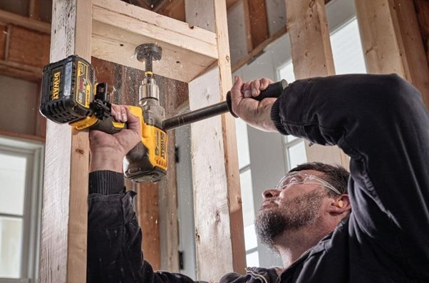 Man using cordless drill to bore hole in wooden frame