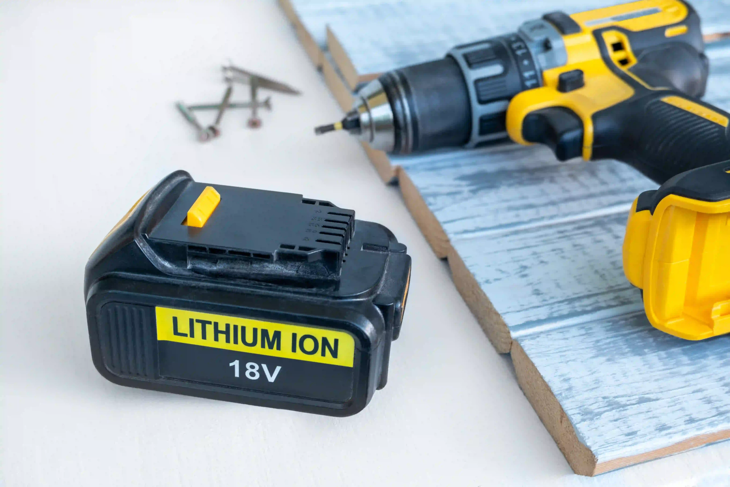 18V lithium-ion battery next to cordless drill and screws