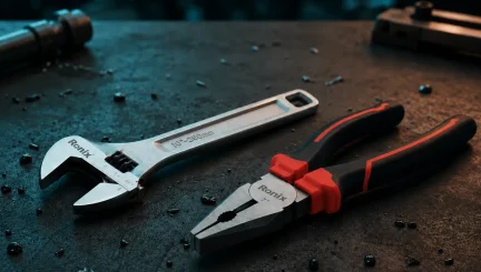 Llave inglesa y alicates Ronix sobre una mesa de trabajo profesional